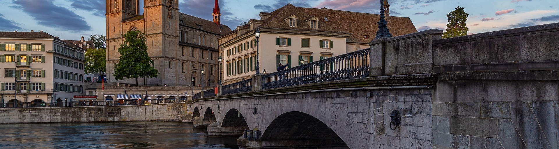 Tagesausflug nach Zürich - malerische Szene in Zürich mit einer historischen Steinbrücke im Vordergrund, die über einen ruhigen Fluss führt
