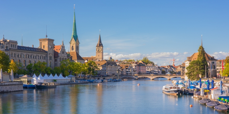 Ausflugsziele in Zürich - Blick auf eine Stadt mit eleganten Gebäuden, Kirchentürmen und einem ruhigen Fluss, der hindurchfließt