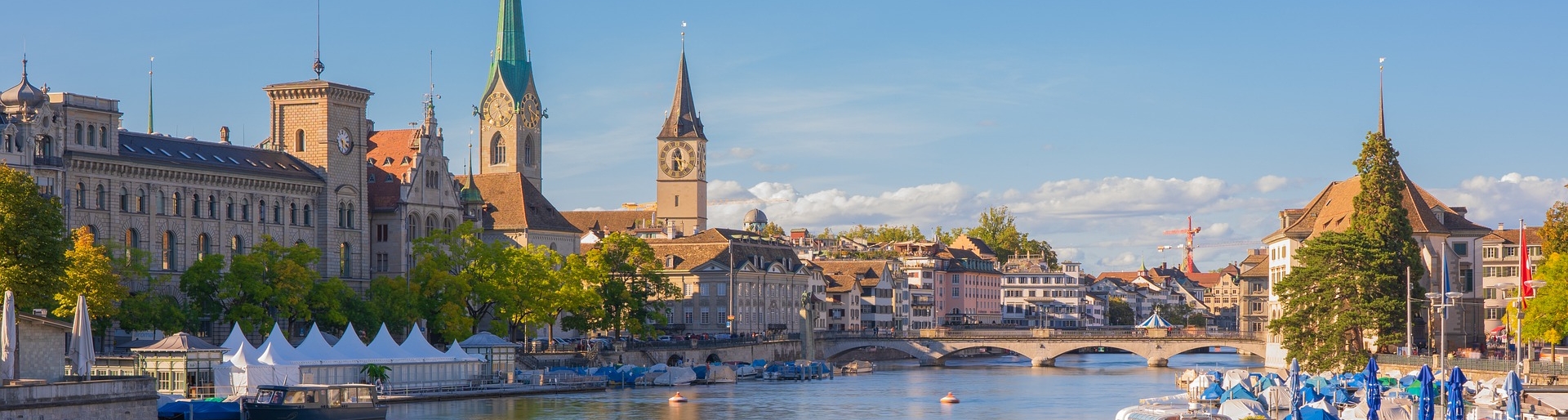 Ausflugsziele in Zürich - Blick auf eine Stadt mit eleganten Gebäuden, Kirchentürmen und einem ruhigen Fluss, der hindurchfließt