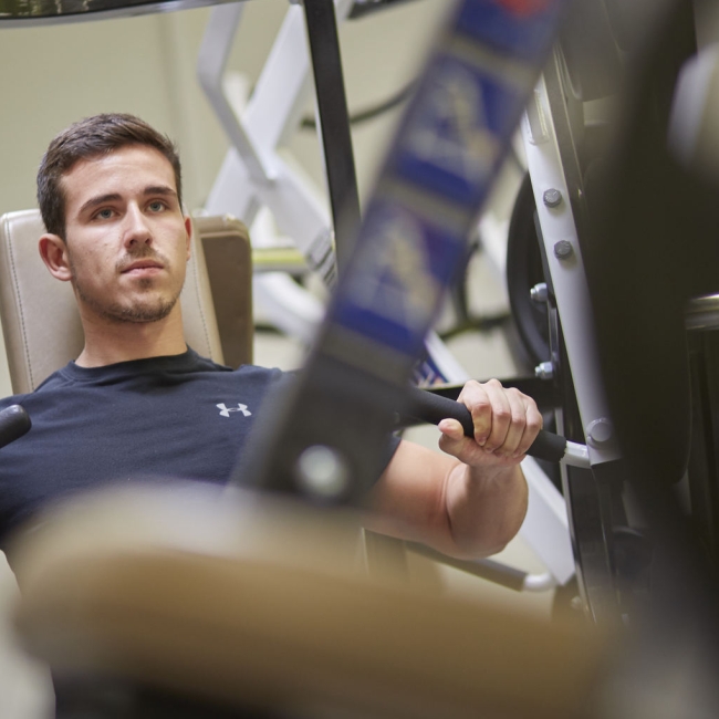Sportler trainiert an einem Kraftsportgerät für den Oberkörper 