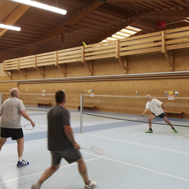 Drei sportliche Männer spielen in der Sporthalle Badminton 