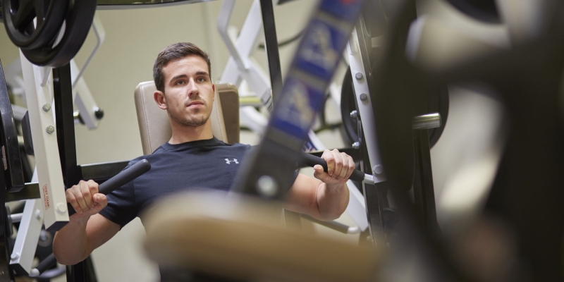 Sportler trainiert an einem Kraftsportgerät für den Oberkörper 