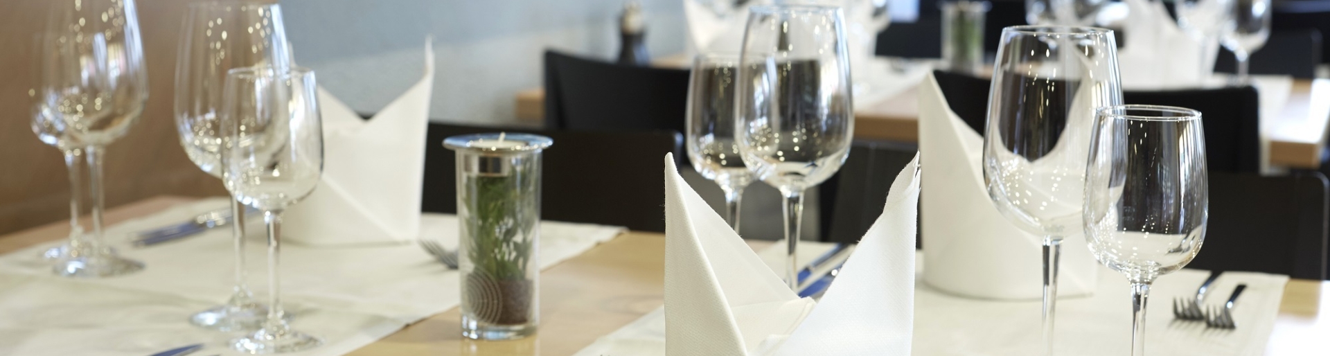 Ein edel angerichteter Tisch mit weißen Servietten und glänzenden Weingläsern.