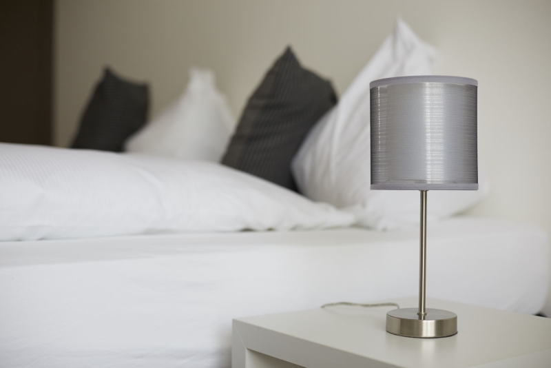 Moderne Bettlampe neben einem Boxspringbett im Aparthotel