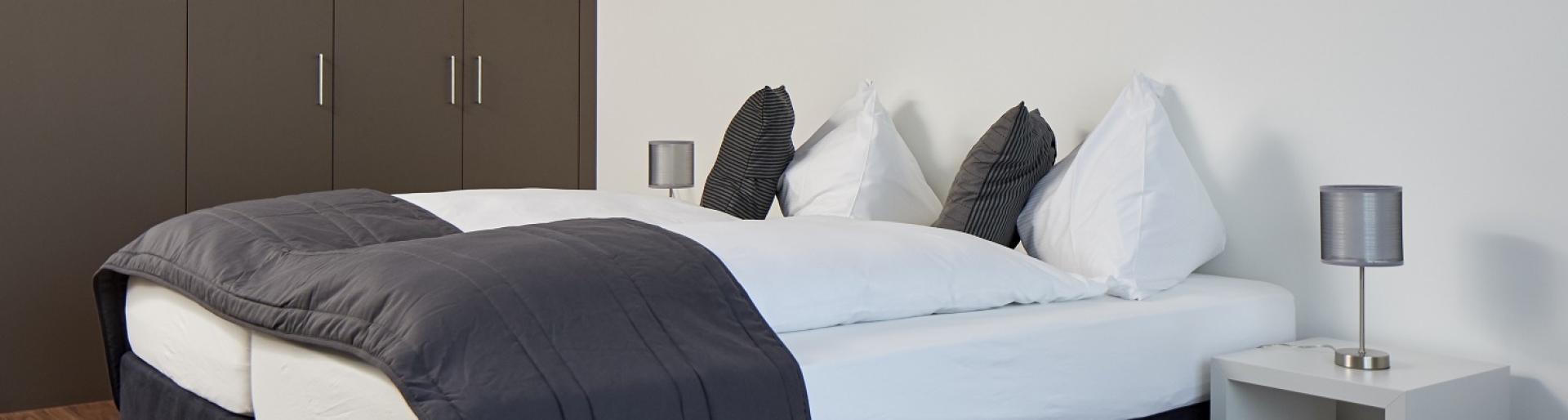 Wohnen auf Zeit - Blick auf ein graues Boxspringbett in einer befristeten Wohnung nähe Zürich 