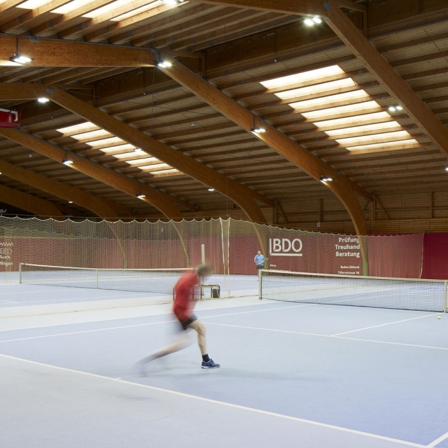 Large indoor tennis centre with some players at the sports hotel in Switzerland